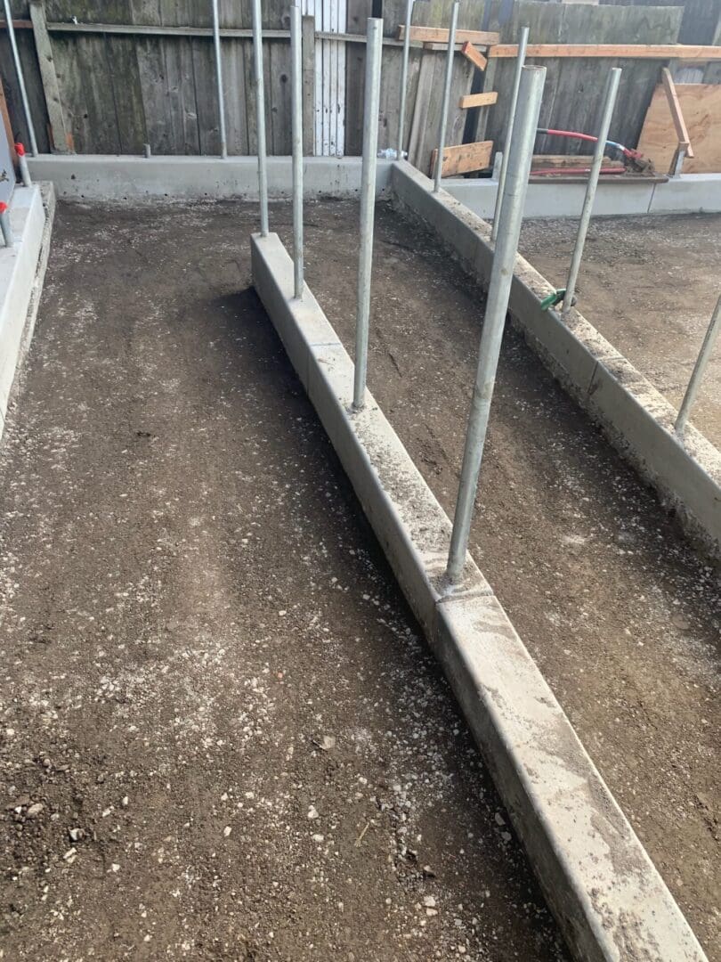 A concrete walkway with metal posts and cement.
