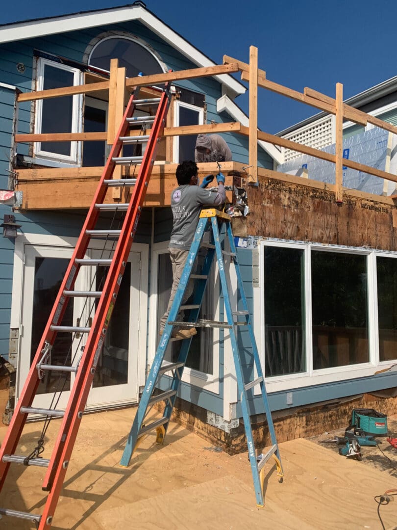 A man on a ladder working on the roof of a house.