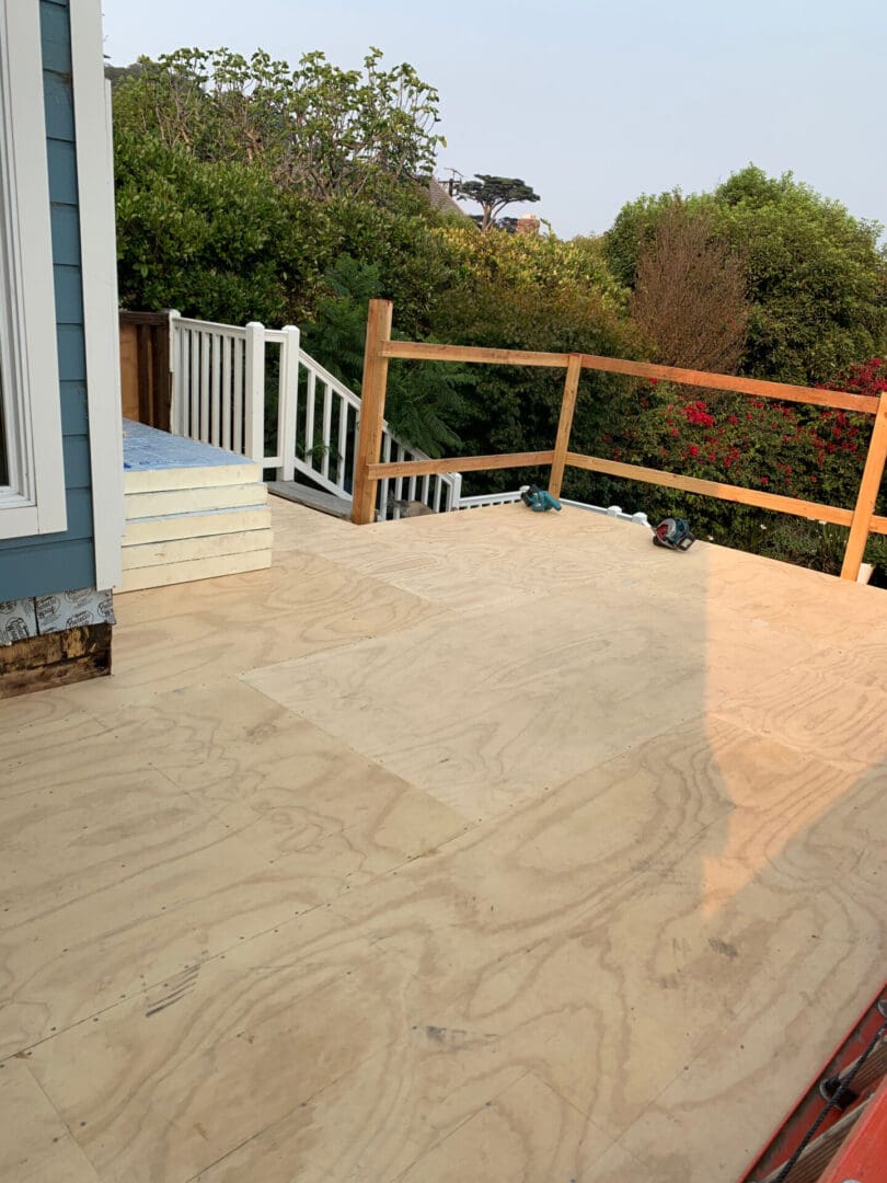 A deck with wood flooring and a wooden railing.