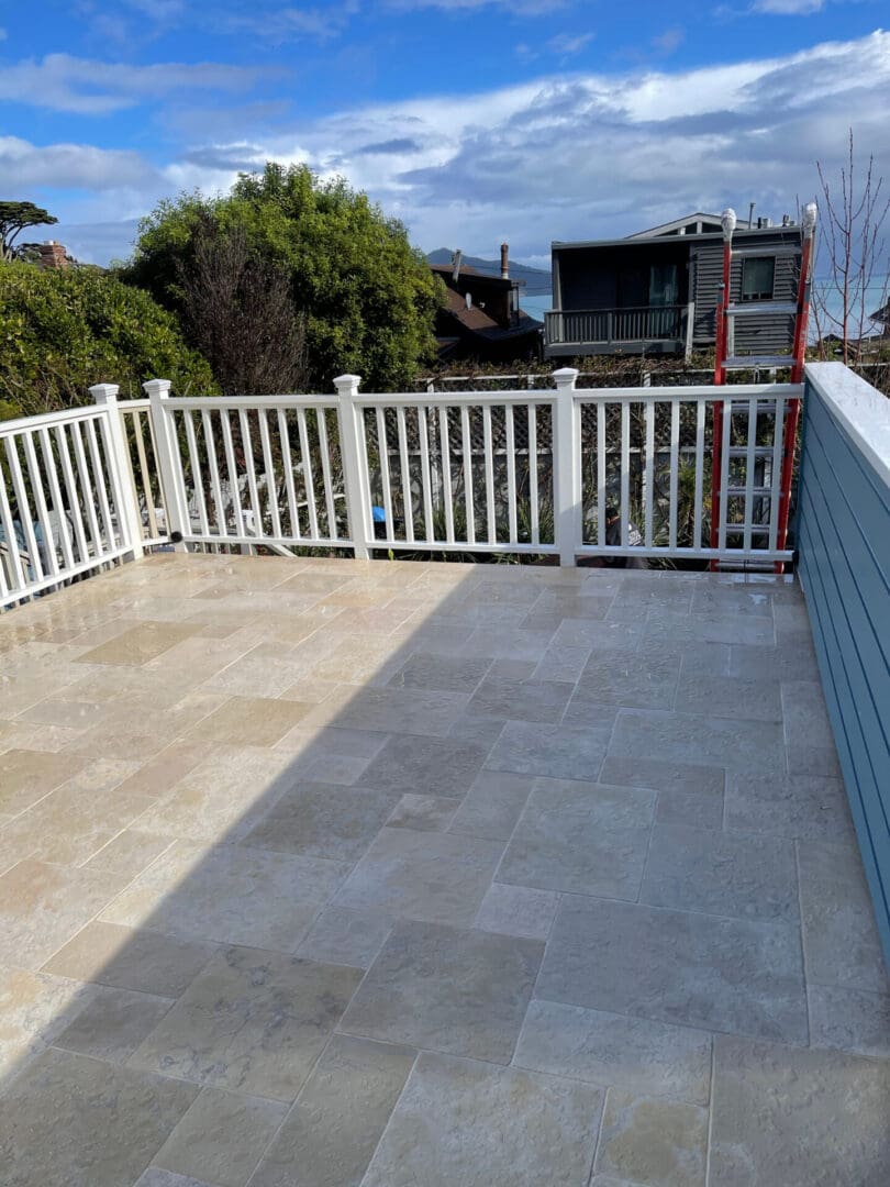 A deck with white railing and blue wall.