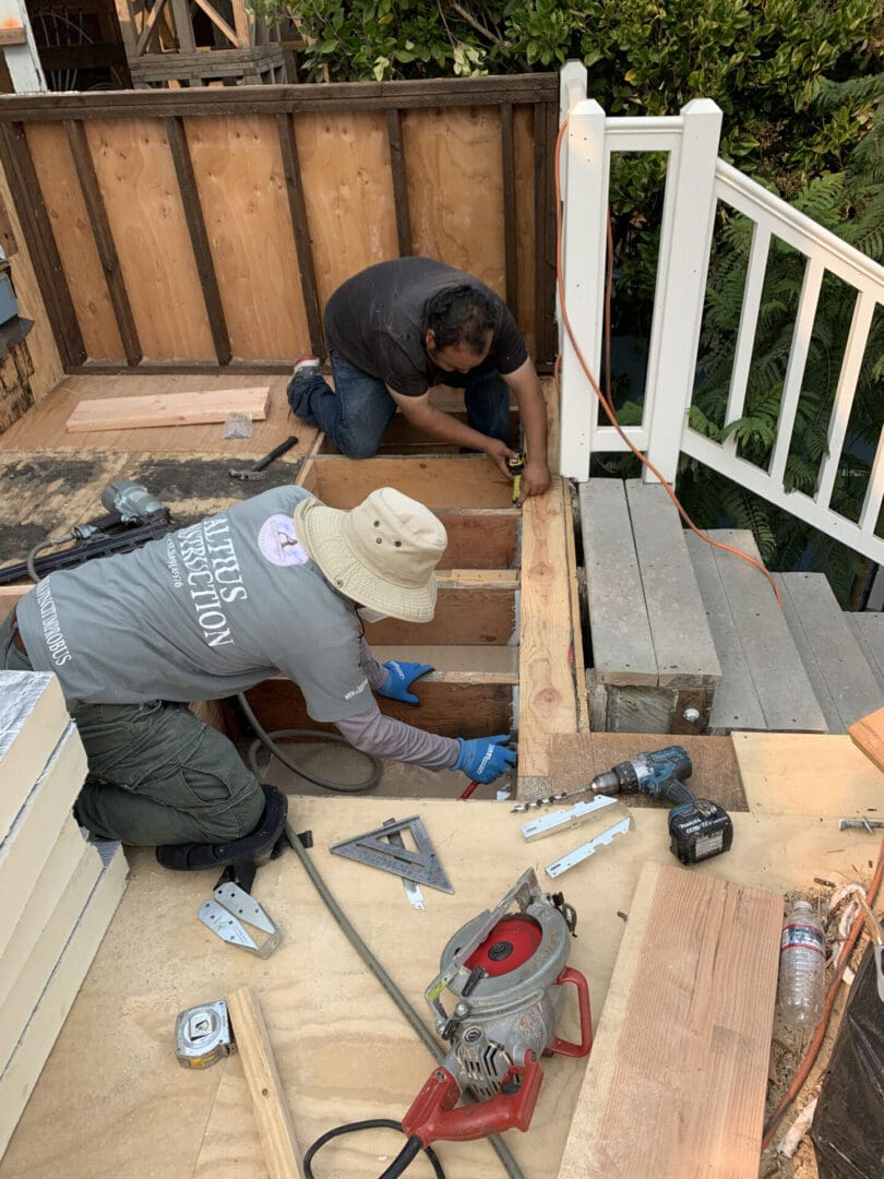 Two men working on a wooden staircase.